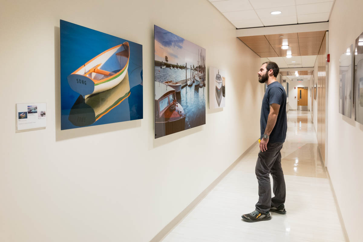 man standing in long hallway looking at a group of three large acrylic face-mounted prints