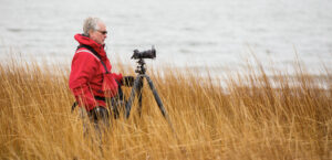 image of phil nelson standing in sea grass with his camera